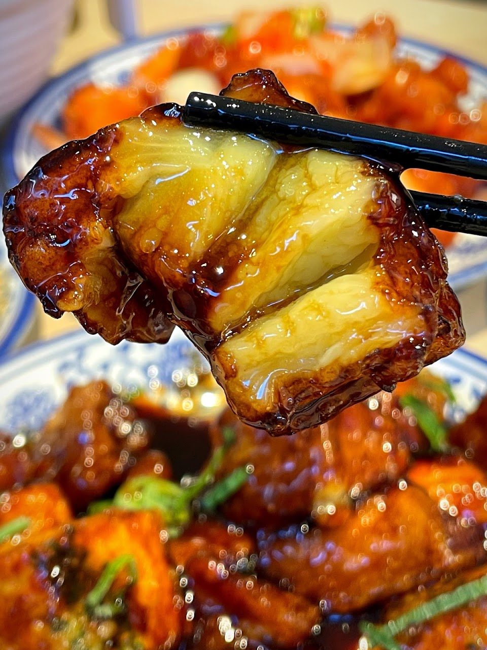 Glossy honey chicken held with chopsticks