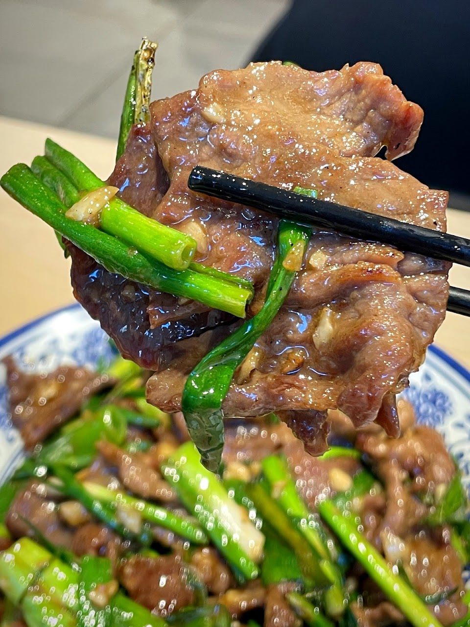 Beef stir-fry with greens held by chopsticks